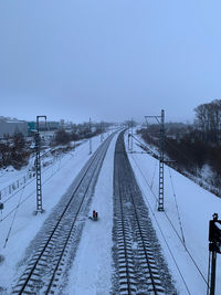 Train on snow covered railroad tracks against sky during winter