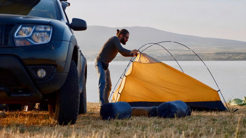 Man standing at tent against sky