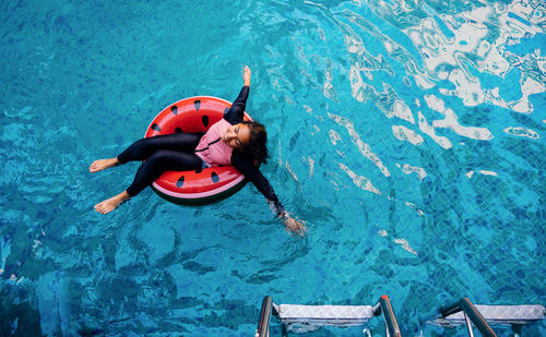 High angle view of girl floating on inflatable ring in swimming pool