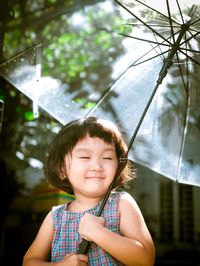 Cute smiling girl with eyes closed holding umbrella