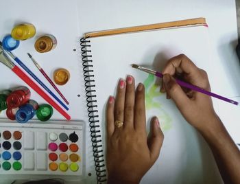 Cropped image of hand holding colored pencils on table