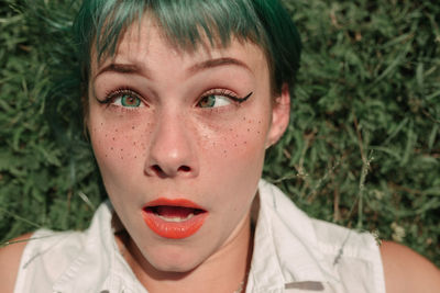 Close-up of young woman with green eyes lying on field