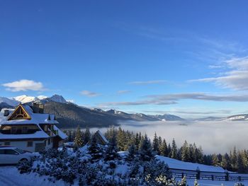 Houses and mountains against blue sky during foggy weather at zakopane