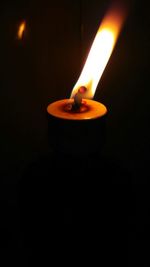 Close-up of lit candle in dark room