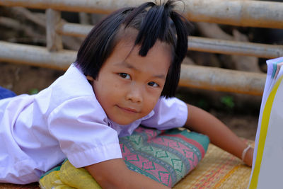 Schoolgirl reading book while lying on wooden bridge