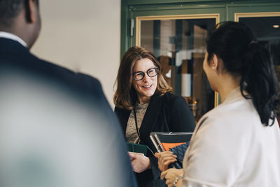 Smiling businesswoman discussing with colleagues at office