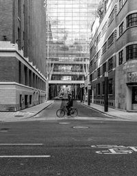 Man riding bicycle on road amidst buildings in city