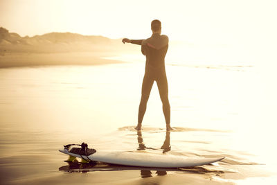 Man standing on beach against sky during sunset