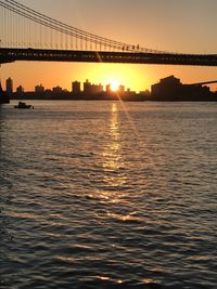 View of suspension bridge over river at sunset