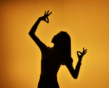 Low angle view of silhouette woman standing against orange sky