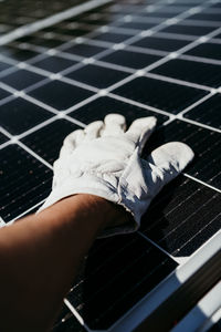 Hand of mature technician man touching solar panels on house roof for self consumption energy