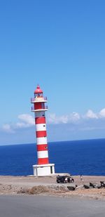 Lighthouse by sea against sky