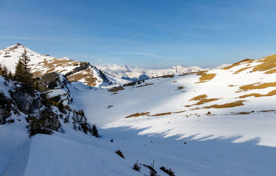 Scenic view of snow covered mountains against blue sky