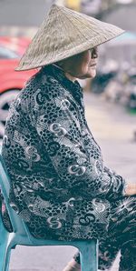 Portrait of old vietnamese woman wearing hat while sitting on chair