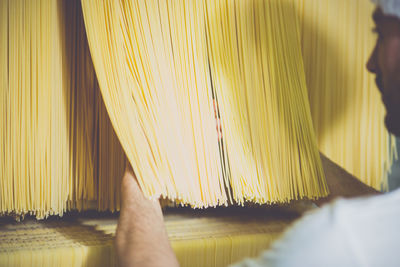 Cropped image of person checking spaghetti drying in factory