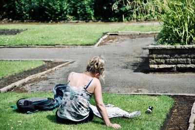 Rear view of woman sitting on grass in park