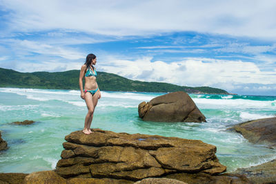 Full length of man on rocks at beach against sky