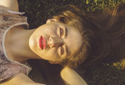 Portrait of beautiful woman lying on grass at park