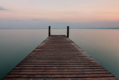 Pier over sea against sky during sunset