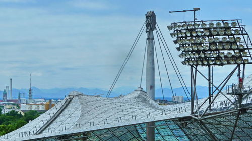 Electricity pylon by harbor against sky in city