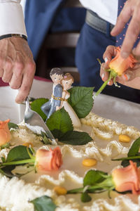 Midsection of man cutting wedding cake