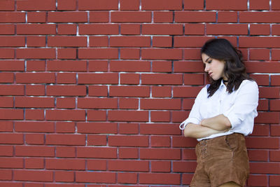 Woman standing against brick wall