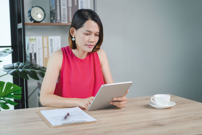 Young woman using phone while sitting on table