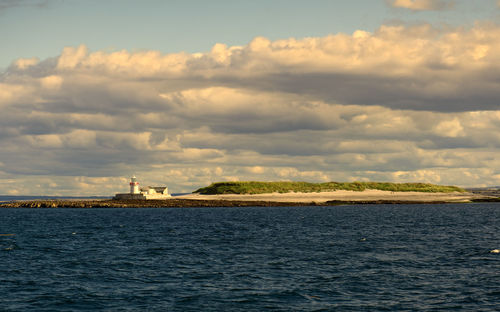 Seascape scenery of lighthouse under dramatic cloudy skies at aran islands in ireland 