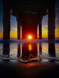 Silhouette bridge over sea during sunset