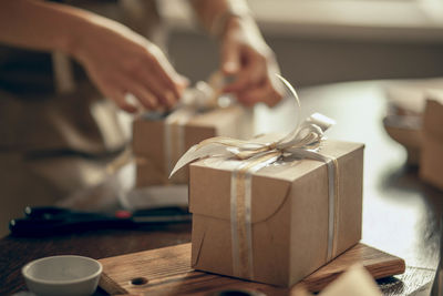 Craft box with white and gold ribbons.  woman's hands ties ribbon on customer's order box,  delivery