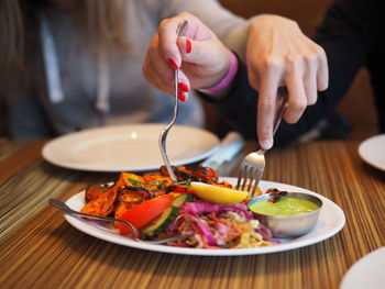 Midsection of person holding food in plate on table