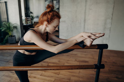 Woman with leg on railing stretching at gym