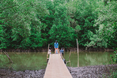 Rear view of man amidst plants in lake