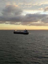 Boat sailing in sea against sky during sunset