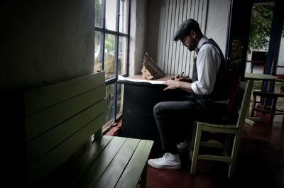 Side view of young man sitting on chair at home