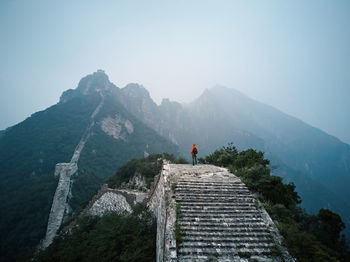 Man standing on great wall of china by mountain against clear sky