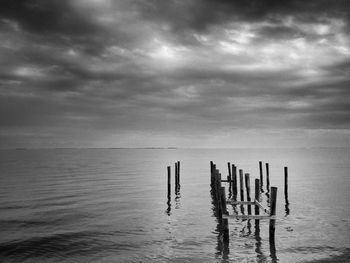 Pier on sea against cloudy sky