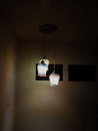 Illuminated pendant light hanging on wall at home