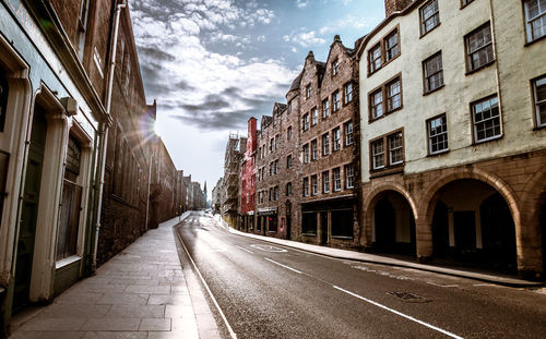 Empty road amidst buildings in city