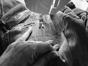 Close-up of woman stitching jeans on sewing machine