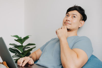 Portrait of young man sitting on potted plant