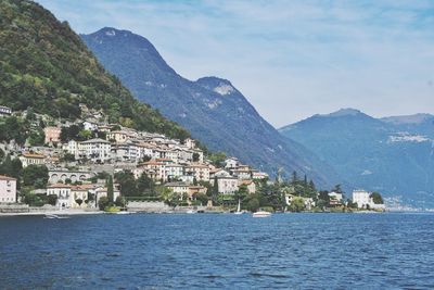 Town by sea and mountains against sky