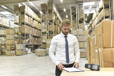 Businessman with clipboard and barcode scanner in warehouse