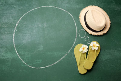 High angle view of blank speech bubble with flip-flops on blackboard