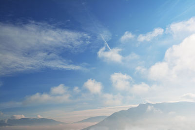 Scenery with mountain range surrounded by clouds and fog