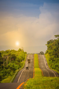 Road amidst trees against sky during sunset