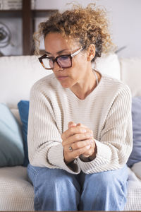 Young woman using mobile phone while sitting on sofa at home