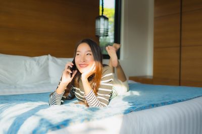 Portrait of young woman lying down on bed