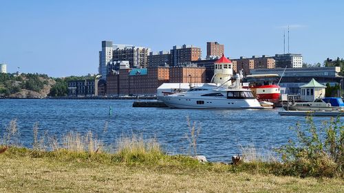 Sailboats moored on river by buildings in city against sky