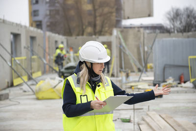 Woman construction site engineer architect worker with hard hat writes notes on the progress of work